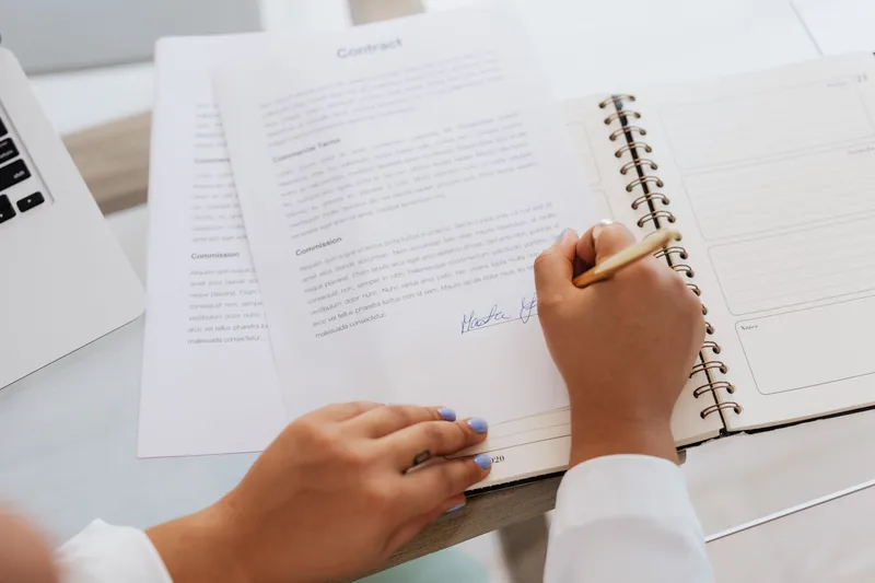 Hands signing a data protection agreement next to a laptop